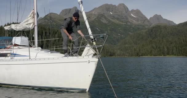 Sailing Alaska Man Pulling Rope Bow Sailboat Scenic Coastline Basckground — Stockvideo