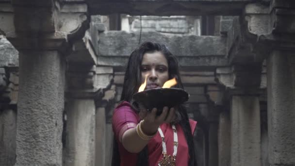 古い階段で美しいインドの女の子伝統的なインドの赤ののこぎりを身に着けています 金のジュエリーや火災プレートを保持バングル デュルガの撮影コンセプト インドのダンスの姿勢でインドの女の子ダンサー — ストック動画