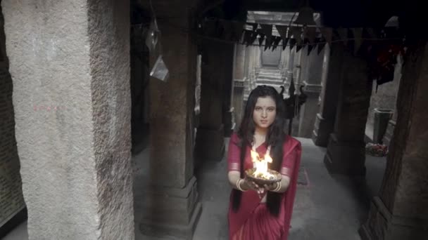 古い階段で美しいインドの女の子伝統的なインドの赤ののこぎりを身に着けています 金のジュエリーや火災プレートを保持バングル デュルガの撮影コンセプト インドのダンスの姿勢でインドの女の子ダンサー — ストック動画