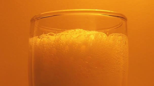 Gros Plan Mousse Bière Verre Sur Fond Orange Statique — Video