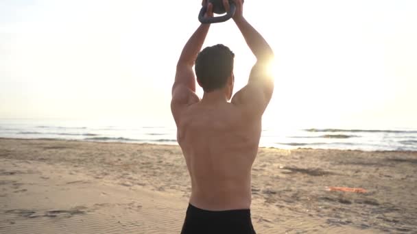 Hombre Sin Camisa Entrenando Con Kettlebell Playa Amanecer Cámara Lenta — Vídeos de Stock