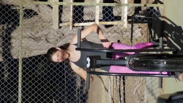 Young Woman Smiling While Preparing Exercise Air Bike Vertical Video — Stock videók