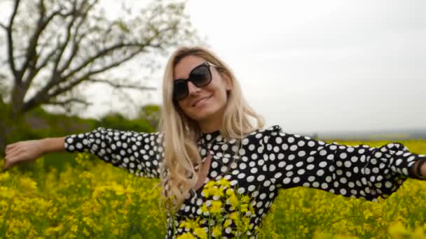 Güneş Gözlüklü Mutlu Kadın Elinde Çiçekle Kanola Tarlasında Kaldırıyor — Stok video