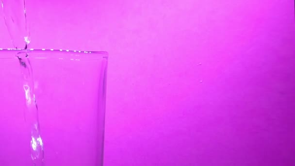 Water Being Poured Glass Left Video Purple Background Static — Stockvideo