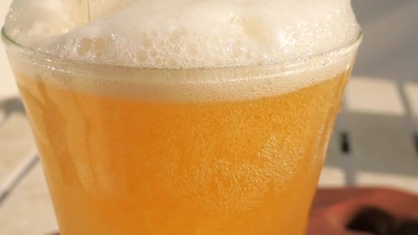 すべての小さな泡と明るい白い泡を表示するクローズアップのビールガラスのトップ ゆっくりとした動きは ガラスの側面を滑る泡をキャプチャします ビールやその他の飲料コンセプト映像 — ストック動画