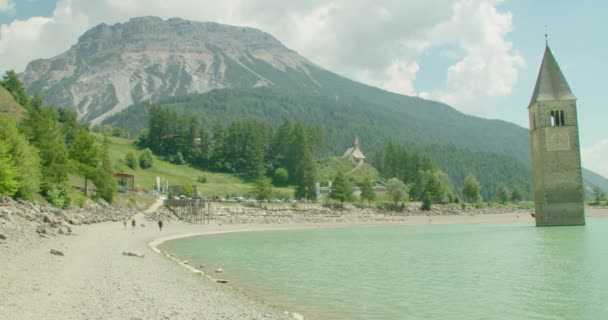 Steady Shot People Walking Shore Reschensee Sunny Day Italy Kirchturm — Stok video