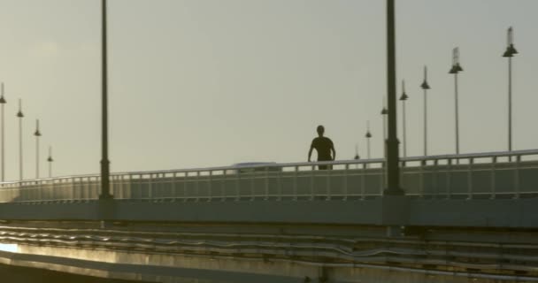 Silhouette Person Riding Electric Scooter Bridge Golden Hour Sunlight — Video