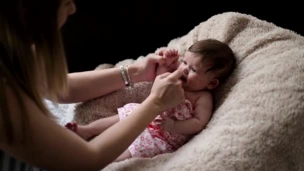 Mother Dresses Baby Girl While She Lying Wool Covered Pillow — Stockvideo