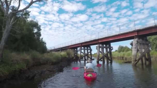 Tracking Shot Man Red Kayak Paddling River Old Bridge Extending — Stockvideo