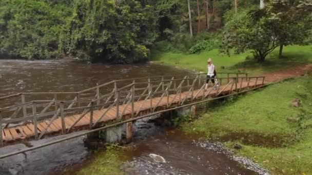 Aerial Shot Orbiting Young Blonde Woman Crossing Old Wooden Foot — Vídeos de Stock