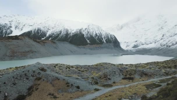 Panning Shot Glacial Lake Surrounded Snow Capped Mountains Cold Winters — Vídeos de Stock
