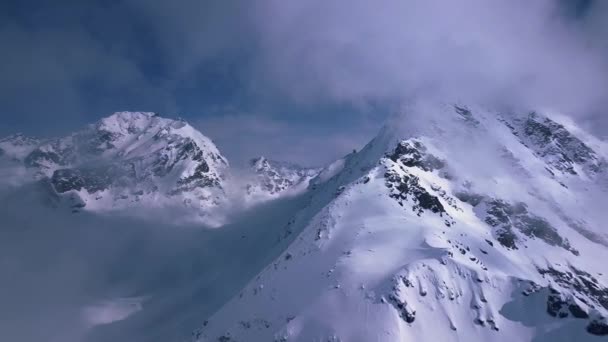 瑞士凡尔比耶 一架无人驾驶飞机向笼罩在云彩中的一座戏剧性的雪山飞去 — 图库视频影像