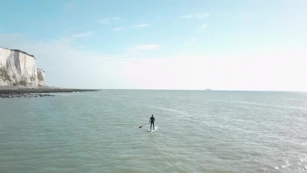 Young Man Stand Paddle Boarding Sea Drone Pans Out Right — стоковое видео