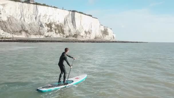 Young Man Stand Paddle Boarding Sea Drone Pans Out Right — Stockvideo