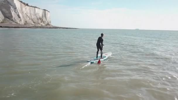 Young Man Stand Paddle Boarding Sea Drone Pans Out Right — Stockvideo