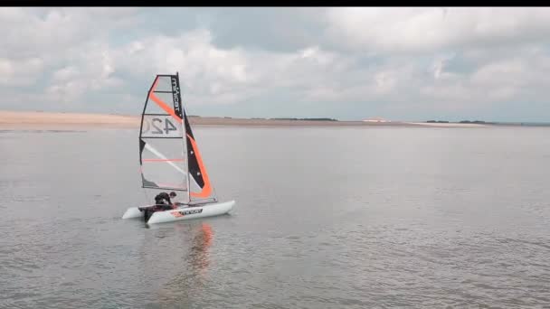 Man Sailing His Catamaran Sea Retracting Sail Drone Pans Side — стоковое видео