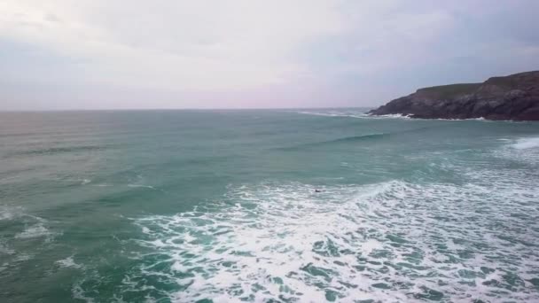 Surfer Swimming Choppy Waves Alongside Headland Drone Shot — Stockvideo