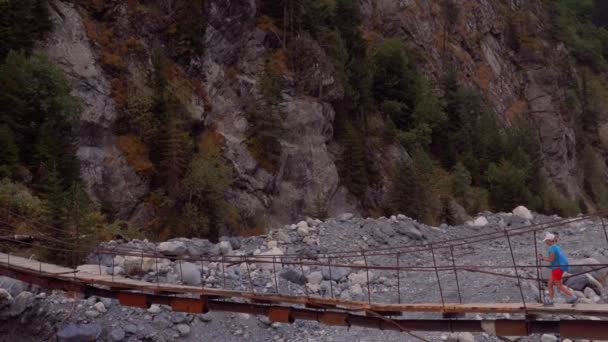 Tourist Girl Crossing Old Bridge Wild Glacial River Caucasus Mountains — Vídeos de Stock