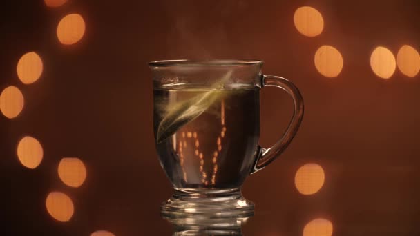 Green Tea Bag Being Dropped Steaming Glass Mug Beautiful Bokeh — Stockvideo