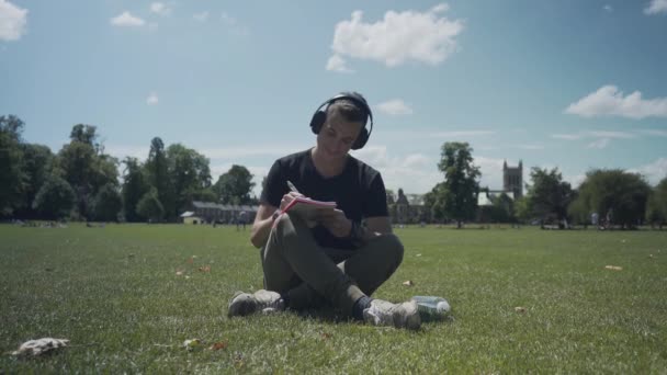 Young White Man Seated Grass Making Notes His Notebook Park — 图库视频影像