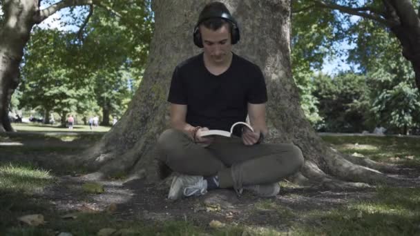 Young White Man Seated Tree Reading Book Park Cambridge City — Vídeo de stock