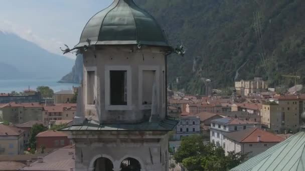 リヴァ ガルダの教会のめまい効果イタリアのアルプスと背景のガーデラーク 北イタリアの教会の塔のドローンショット — ストック動画