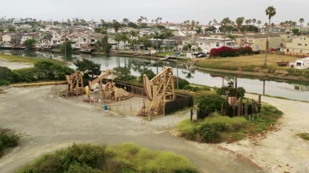 Aerial View Rotates Set Oil Pumpjacks Beachfront Channel Houses Nearby — Stock video