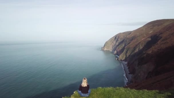 Беспилотник Над Головой Молодой Женщины Сидел Краю Прибрежной Скалы — стоковое видео