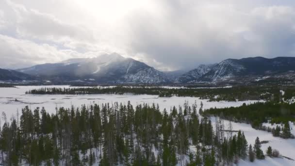 Aerial Moving Left Reveal Icy Frozen Lake Surrounded Snow Green — Stock videók