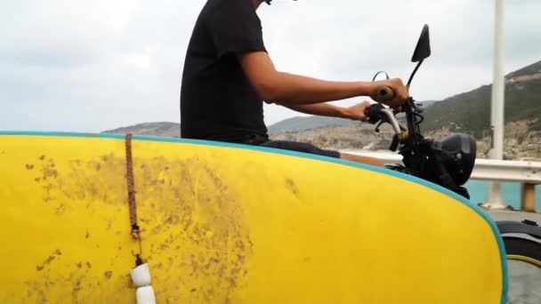 Young Man Drives Motorcycle Yellow Surfboard Attached Looking Ideal Spot — 图库视频影像
