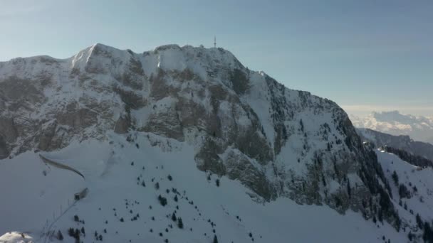 遠くの電波塔に向かって雪に覆われた山頂を飛ぶドローン — ストック動画