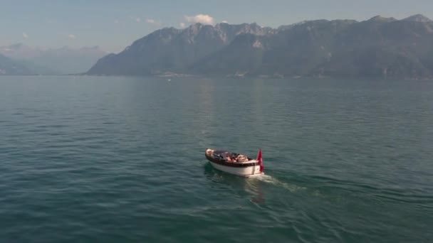美しい青い湖の上を走る小型モーターボートの前を飛ぶドローン — ストック動画