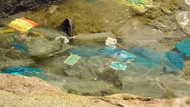 岩の多い海岸の潮溜まりに浮かぶ海洋プラスチックごみ スタティックショット — ストック動画