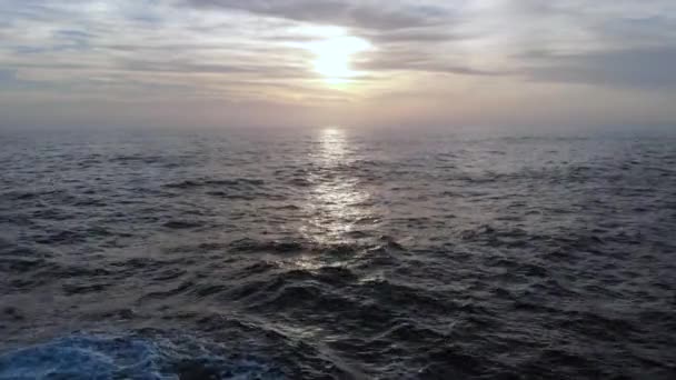 日没時の深い暗い海の表面を飛んで 背景に波の劇的な空中ビューが飛び散ったり 雲や太陽の反射 — ストック動画
