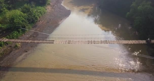 Sliding Drone Shot Suspension Bridge River Motorcycle Crossing Morning Sun — Stockvideo