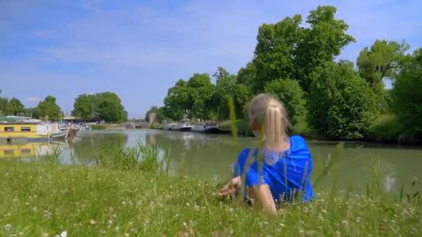 Young Blonde Caucasian Woman Dressed Blue Lying Grass Facing River — 비디오