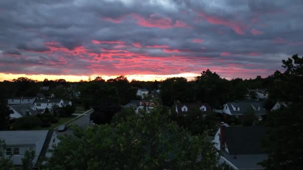 从郊区的后院俯瞰美丽的日落 当摄像机在地平线下轰然落下 金色的落日和五彩斑斓的云朵落在树上时 邻居们的周围一片漆黑 — 图库视频影像