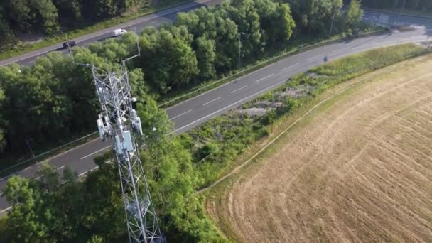 5G放送タワーアンテナ高速道路の背景を走行する車両と英国の田舎までの空中傾き — ストック動画