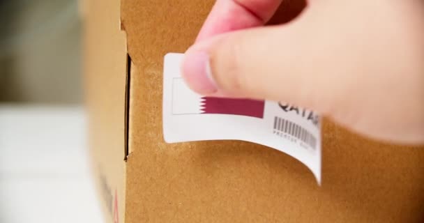 Mãos Aplicando Made Qatar Flag Label Uma Caixa Papelão Transporte — Vídeo de Stock