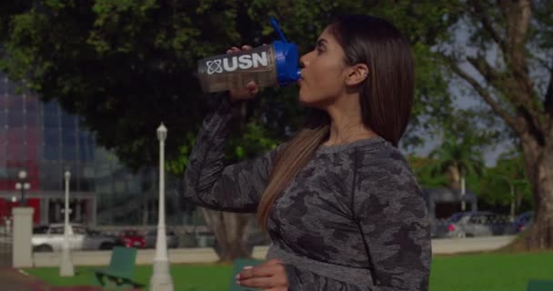 激しいトレーニングの後でフィットネスの女の子は水を飲む — ストック動画