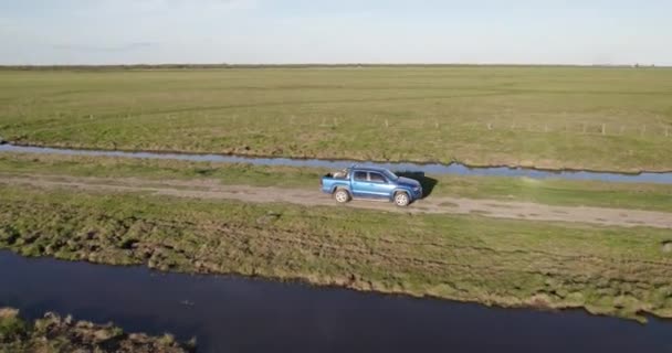 Sininen Pakettiauto Ajaa Lujaa Hiekkatiellä Reunalla Stream Keskellä Kenttää Aurinkoisena — kuvapankkivideo