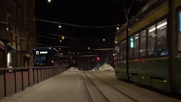 赫尔辛基地铁和公共汽车在晚上穿过雪蒙蒙的冬日街 — 图库视频影像