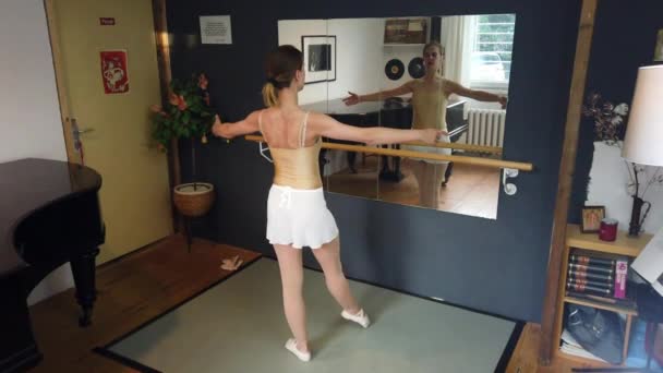 芭蕾舞演员初学者练习基本的舞步 在镜子中修正自己 在柏林芭蕾舞演播室拍摄了一个穿着白色裙子 身材矮小的金发女孩的从容镜头 菲利普 马尔尼茨的4K — 图库视频影像