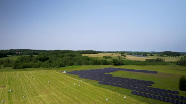 一个小型太阳能电池板农场的空中景观和收割庄稼后被塑料包裹在地里的干草包 — 图库视频影像