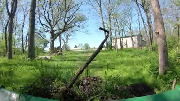 在茂密的森林地区操作绿色小拖拉机的Pov 用装载机铲斗在小径上向新建的大谷仓运送泥土和瓦砾 蓝领工作和乡村生活的概念 — 图库视频影像