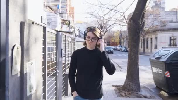 Young Man Glasses Headphones Smiles Walking Listening Music Street — Stockvideo