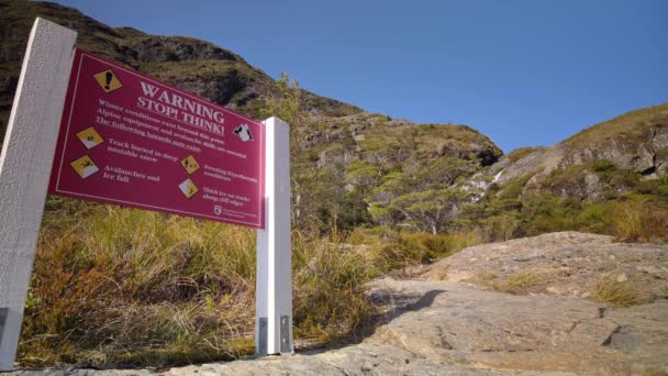 在新西兰的Routeburn赛道上 静止不动的徒步旅行者走过高山警告标志 — 图库视频影像
