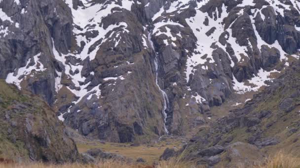 Static Hiker Walks Distant Waterfall Snow Capped Landscape Routeburn Track — Stock Video
