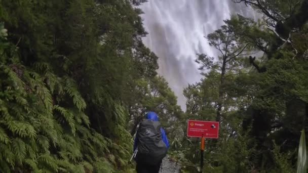 傾斜アップ ウェットハイカーは巨大な荒れ狂う滝に向かって歩く ルートバーントラックニュージーランド — ストック動画