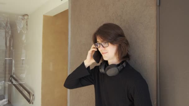 Young Man Glasses Headphones His Neck Talking His Mobile Phone — Stockvideo